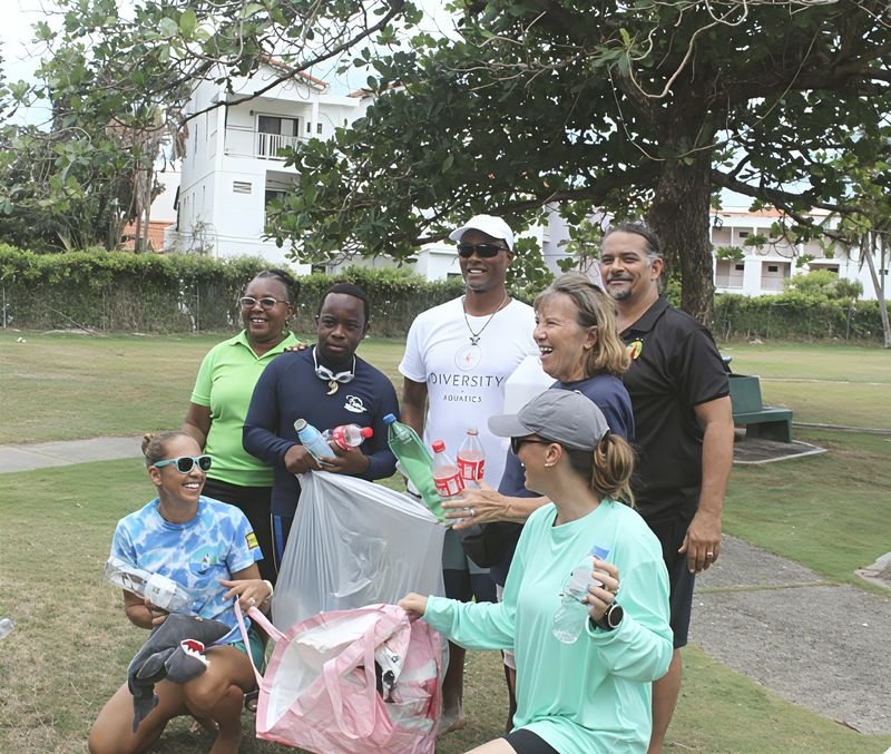 195in365 volunteers of all ages smiling in a park, holding the plastic bottles and bags of rubbish they collected during a community clean-up